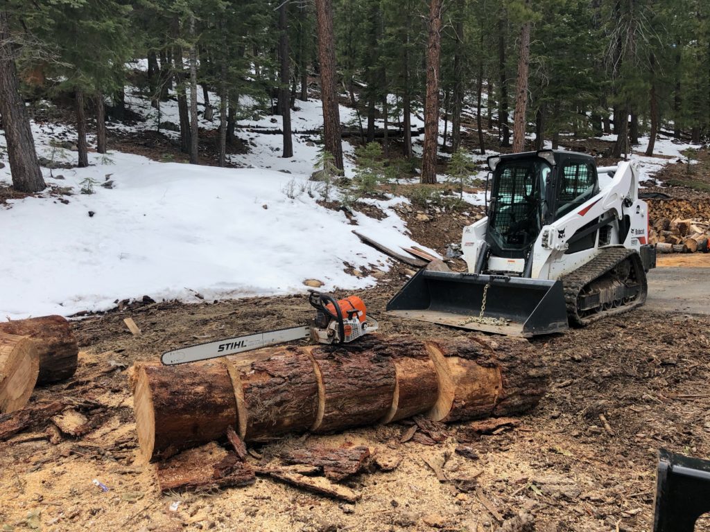 Bobcat compact track loader with cut wood in the foreground